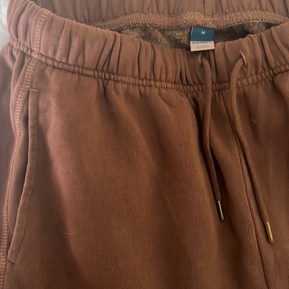 Brown sweatpants/joggers, cuffed bottom with gold details on strings.